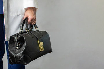 Female physician holding a black leather doctor's bag heading to the office to practice medicine