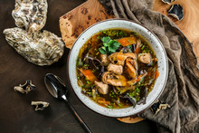 Delicious Soup With Black Chinese Wood Mushrooms And Oysters In Bowl Over Wooden Background With Napkin. Traditional Asian Cuisine. Seafood, Healthy Food, Top View