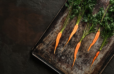 Wall Mural - Fresh carrots for roasting on baking tray on dark background. Fresh vegetables, healthy organic food, harvest, agriculture, top view