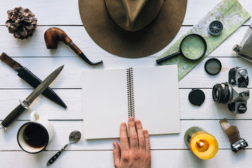 Wall Mural - adventure planning flat lay. travel vintage gear on white wooden table. man hand in frame holding no