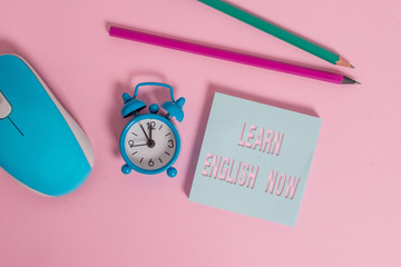 Poster - Text sign showing Learn English Now. Business photo showcasing gain or acquire knowledge and skill of english language Alarm clock wakeup blank notepad mouse markers colored background