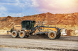 motor grader levels the ground on background of sandy slope on the road construction 