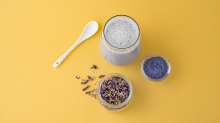  Cup of  blue vegan matcha latte and clitoria flowers on a yellow background