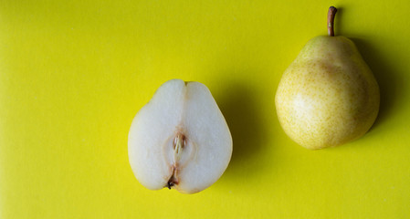 Yellow fresh pear cut in half on yellow background. Top view.