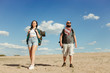 © Vadym - Travel, trekking concept. Touristic lifestyle. Woman and man with backpacks hiking. Tourists traveling through the desert. Copy space