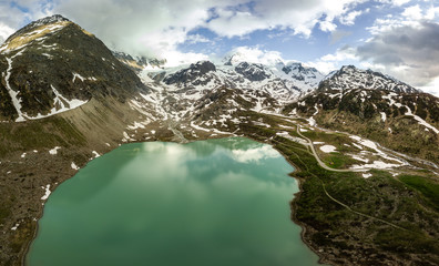 Wall Mural - glacier lake in the swiss alps during spring with clouds, blue sky and snow taken with a drone