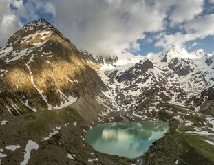Wall Mural - glacier lake in the swiss alps during spring with clouds, blue sky and snow taken with a drone