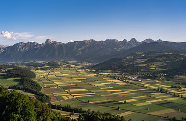 Wall Mural - valley and hills in switzerland during a sunny summer evening with warm light and colorful sky