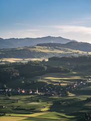 Wall Mural - valley and hills in switzerland during a sunny summer evening with warm light and colorful sky