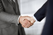 © rogerphoto - Business people in office suits standing and shaking hands, close-up. Business communication concept. Handshake and marketing