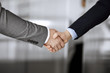© rogerphoto - Business people in office suits standing and shaking hands, close-up. Business communication concept. Handshake and marketing