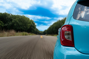 Wall Mural - Close up of rear of blue car drive on the asphalt road wtih nature of tree forest.