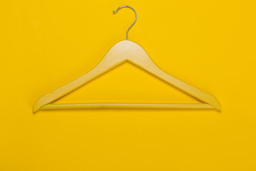 yellow wooden clothes hanger, sale and discounts concept, on a yellow background