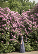 © Milou Dirks - Teenage girl in blue dress standing in front of purple rhododendron tree