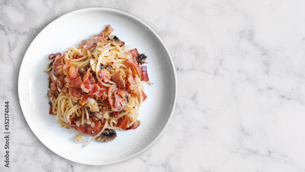 Stir fry Spaghetti bacon with Champion mushroom in white dish on white marble stone table top, with copy space - obrazy, fototapety, plakaty 