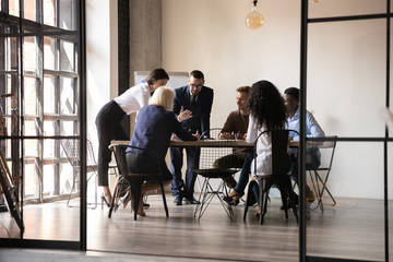 Wall Mural - Diverse employees team engaged in teamwork in modern boardroom, sitting at table in office, reading legal documents, analyzing project statistics, financial report, discussing strategy, planning