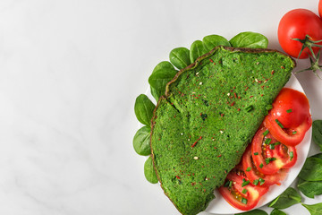 Wall Mural - Healthy breakfast. Green spinach omelet with tomatoes and spices on white marble background. keto diet. top view