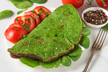 Wall Mural - Healthy breakfast. Green spinach omelet with tomatoes and spices with fork on white marble table. keto diet food