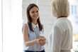 © fizkes - Smiling young businesswoman shake hand of female business partner or client get acquainted greeting in office, happy woman employee handshake colleague coworker closing deal agreement at meeting
