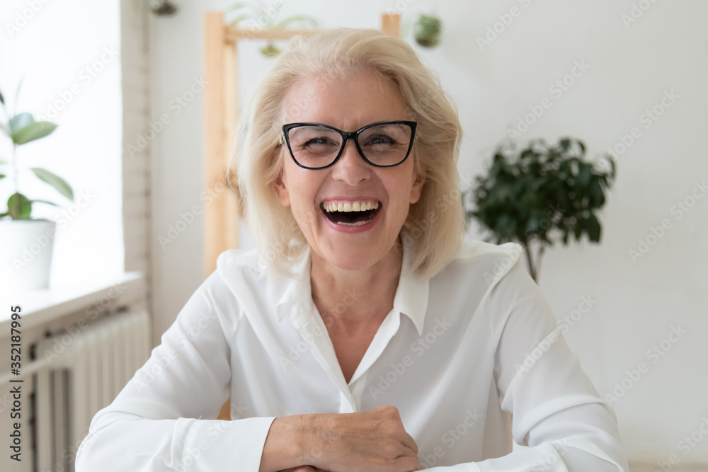 Headshot portrait of excited mature businesswoman in glasses have fun laugh talking on video call, overjoyed happy middle-aged woman employee smile joke speaking online on WebCam conference - obrazy, fototapety, plakaty 