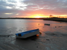 Boats Moored On Shore At Beach Against Sky During Sunset