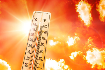 orange sky with bright sun and thermometer symbolizing climate change and global warming