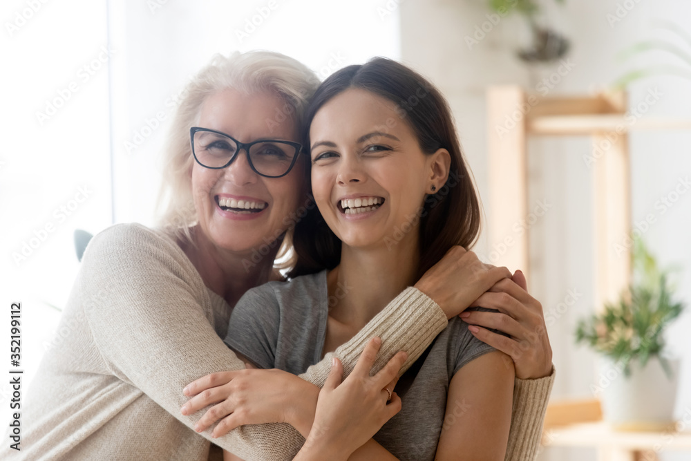 Portrait of happy senior 60s mom and grown-up daughter hug cuddle enjoy weekend time together, smiling mature mother and adult millennial girl child embrace show love and care in relationships - obrazy, fototapety, plakaty 