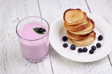 Sticker - Tasty beautiful pancakes with blueberries and blueberry yogurt in a glass cup on a light wooden background with mint leaves. The concept of a healthy diet and a great breakfast