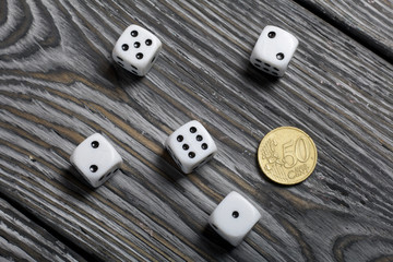 Dice in white with black dots and a coin. On brushed pine boards.