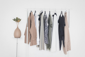 a rack with stylish clothes next to a white wall in the room. clothing retails concept. advertise, s