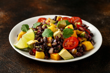 Wall Mural - Avocado, mango salad with black bean on white plate