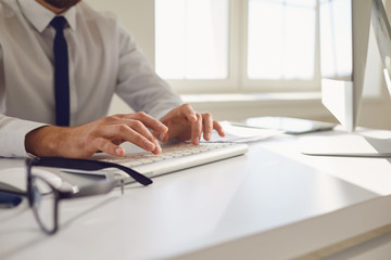 Work online. Busy faceless worker is typing at workplace using computer in office.