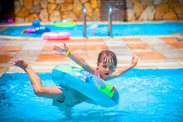 funny image of little cute girl having funn in the outdoor pool at the resort. summer holiday and ha