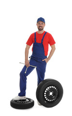 Poster - Full length portrait of professional auto mechanic with lug wrench and wheels on white background