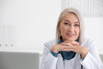 Wall Mural - Portrait of mature female doctor in white coat at workplace