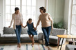 © fizkes - Happy three generations of women have fun dancing holding hands together in living room, overjoyed little girl with young mom and senior grandmother feel energetic active relaxing on weekend at home