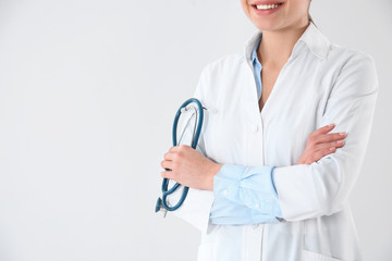 Wall Mural - Young doctor with stethoscope on white background, closeup