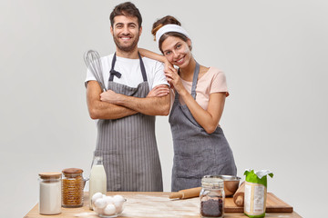 Wall Mural - Happy friendly team of professional chefs pose together at kitchen, satisfied with good work, prepare meal, stand next to each other, use different ingredients bake confectionery for breakfast at home