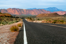 Road In The Desert Of Utah Shot Low Angle In The Middle Of The Road With Rocky Red Mountains As Background 