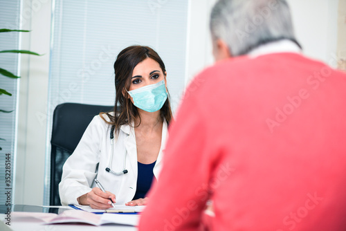 Fotomural Masked doctor listening to a patient