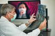 © jovannig - Doctor looking at xray scan of female patient in videocall. Coronavirus world emergency concept
