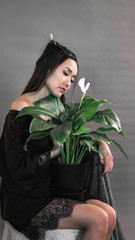 girl on a gray background holding a live green flower