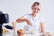 © sata_production - Smiling woman making cereal with milk