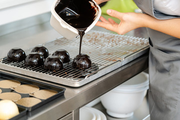 Pastry chef pouring liquid chocolate over a sweet dessert