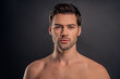 © Roman - Handsome young bearded man isolated. Portrait of shirtless muscular man is standing on grey background. Men care concept.