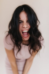 Wall Mural - Portrait of angry brunette screaming at camera. Lady in beige outfit posing emotionally