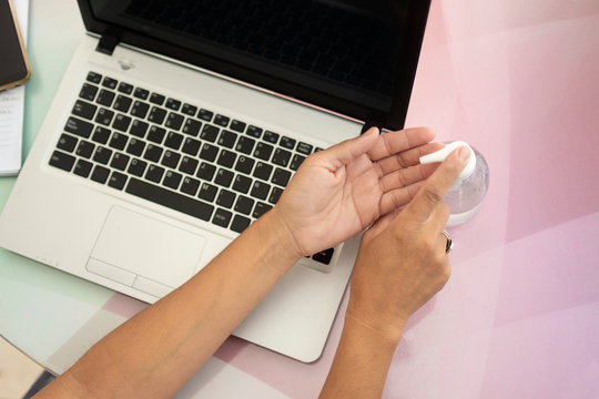 manos con alcohol en gel trabajando en casa por el covid-19 con una laptop 
