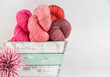 Skeins of pink yarn in a wooden bucket