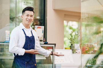 Sticker - Portrait of young positive Vietnamese man welcoming clients in his cafe