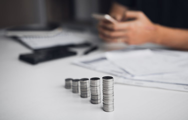 Wall Mural - Asian men are calculating about finances about the cost or future investment at home while the coins are arranged with the idea of saving.